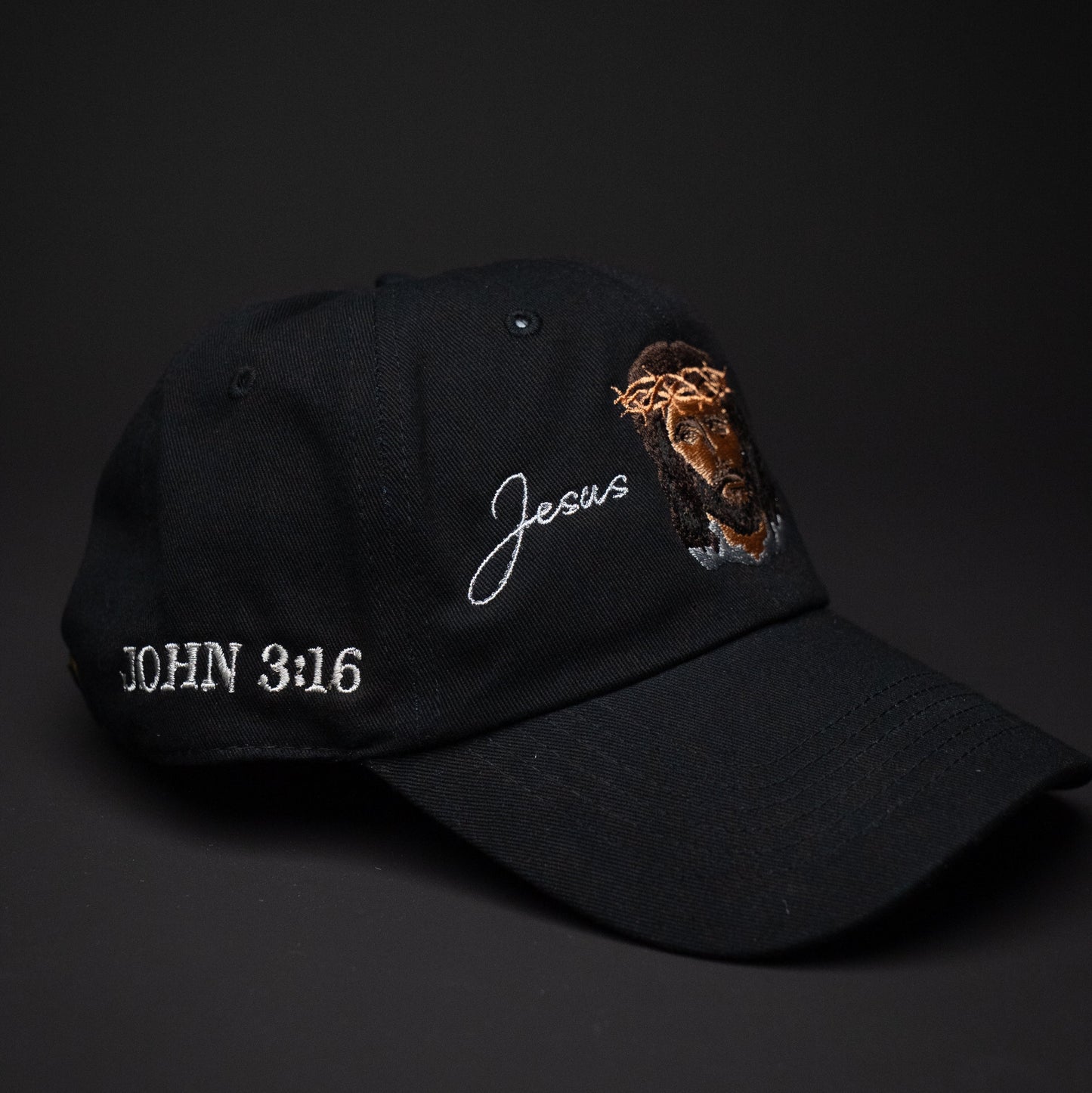 Black cap with 'Jesus' and 'John 3:16' text on a dark background
