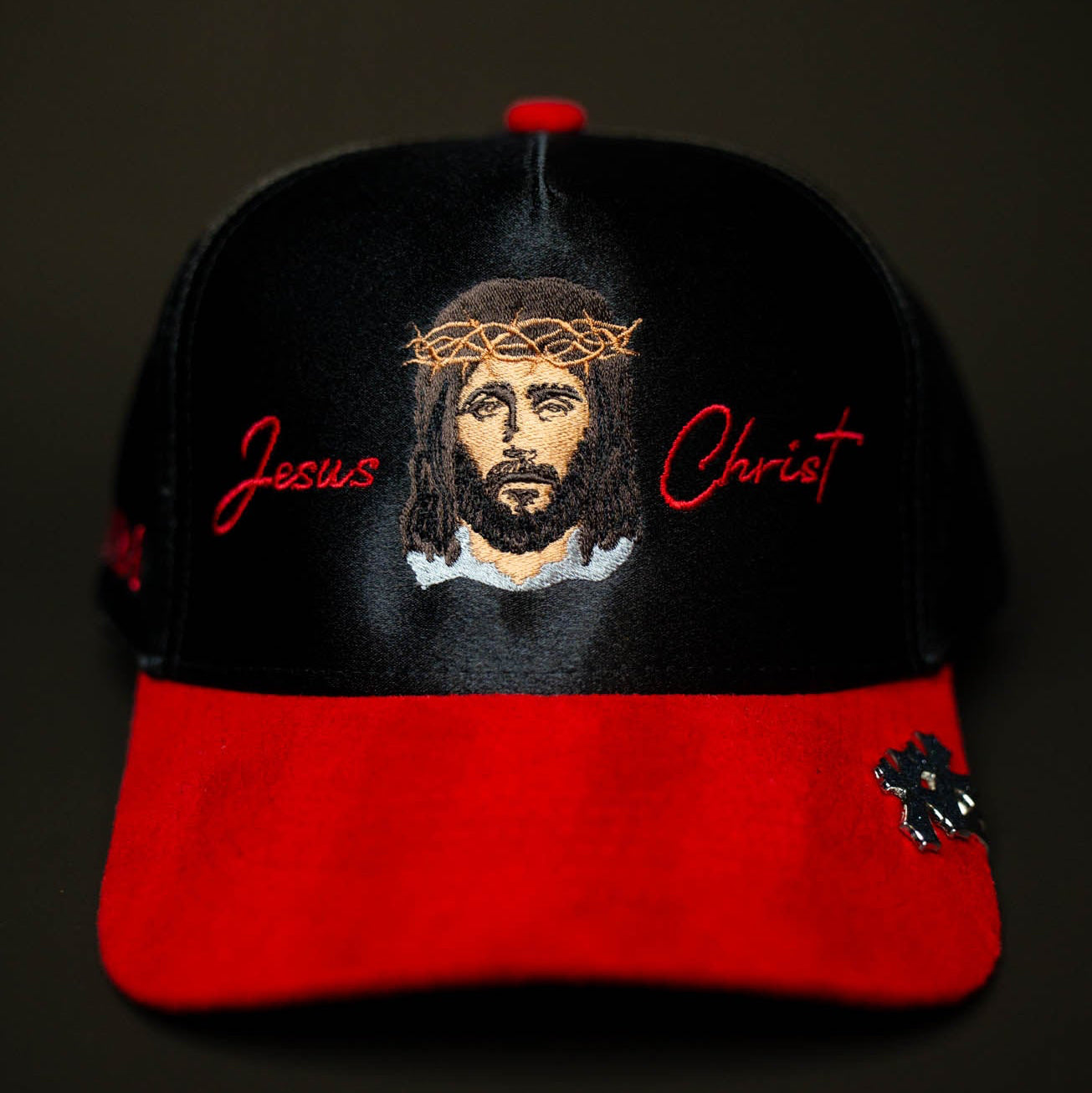Cap with embroidered face of Jesus Christ and 'Jesus Christ' text on a black and red background