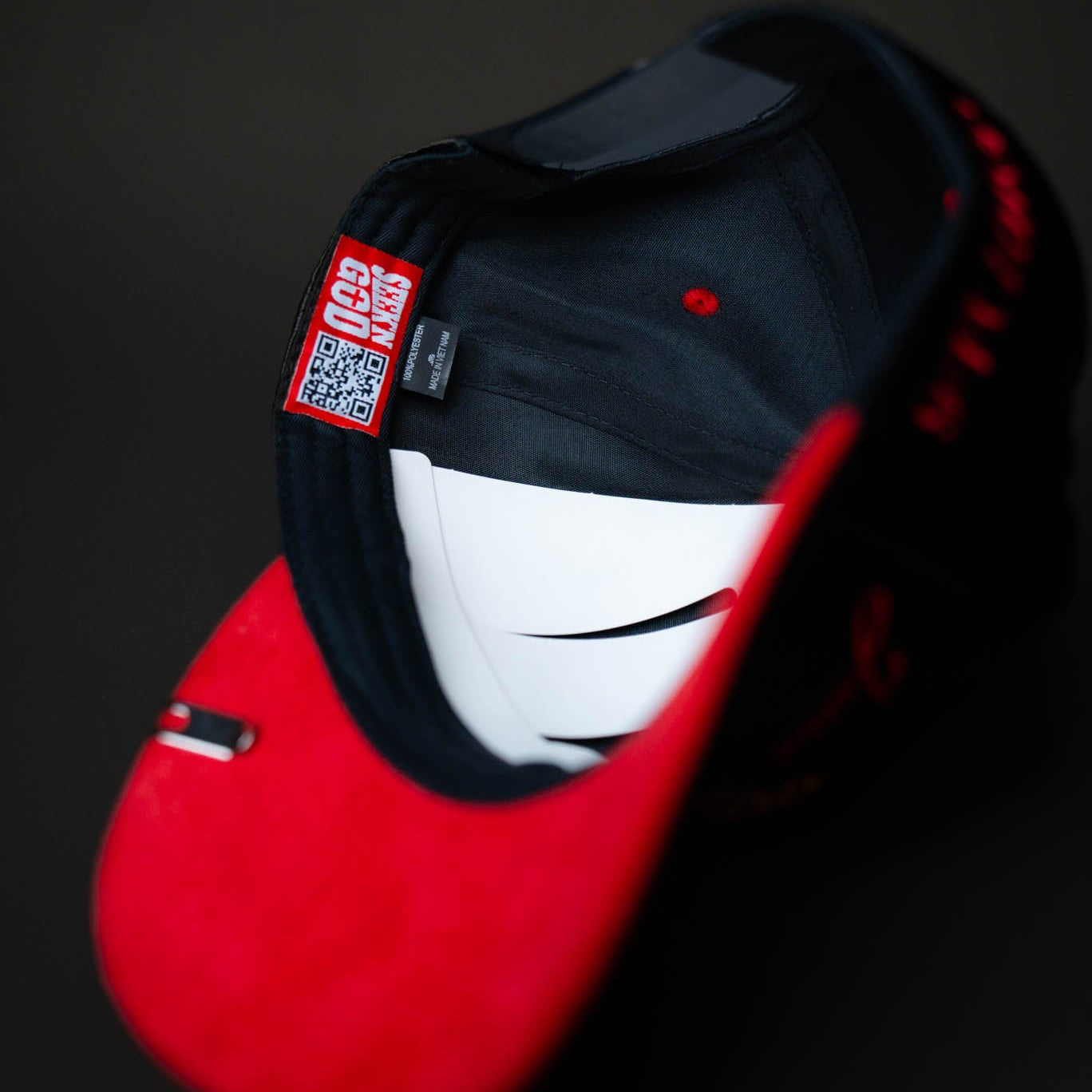 Black and red cap with a QR code label on a dark background
